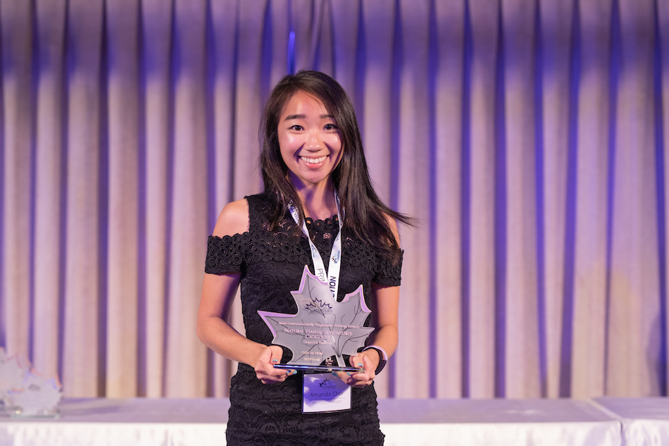young woman holding award on stage