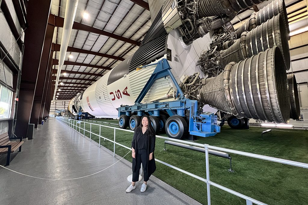 young asian woman in front of rocket ship display