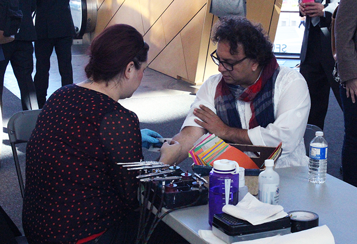 Restaurateur Vikram Vij, the most recent addition to the "Dragons" on CBC's Dragon's Den, receives an airbrush tattoo at the launch of the 2014-2015 TYE Surrey and Vancouver programs. 